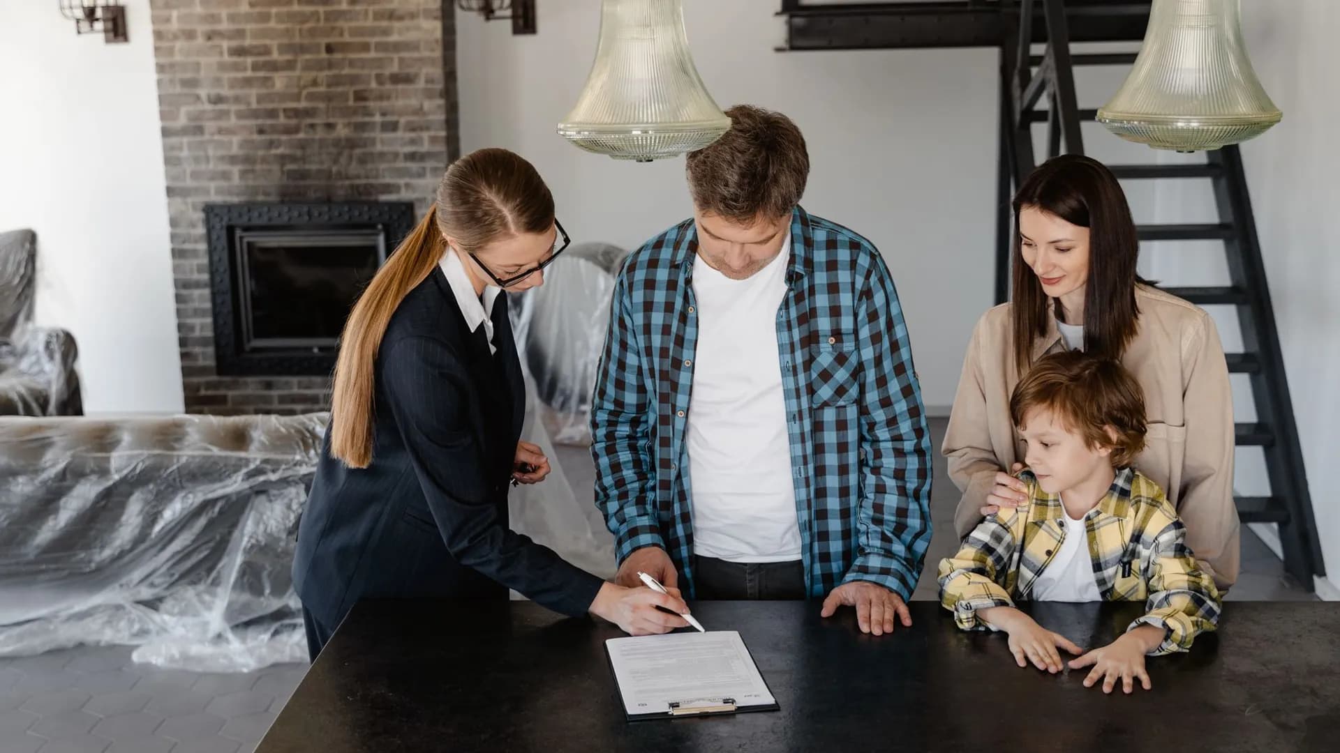 Happy family signing a real estate contract with agent inside their new home.