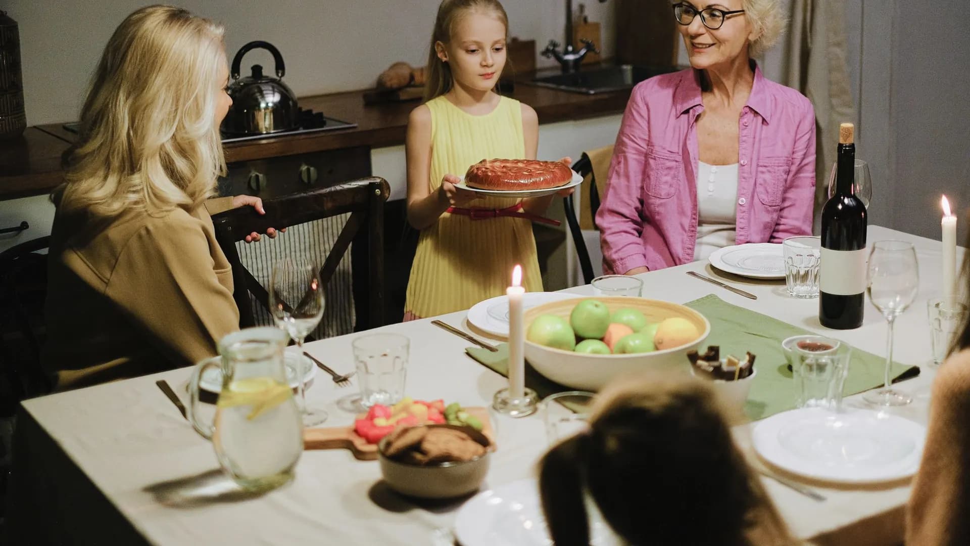 A joyful family dinner with cake and wine, featuring generations gathered around a table.