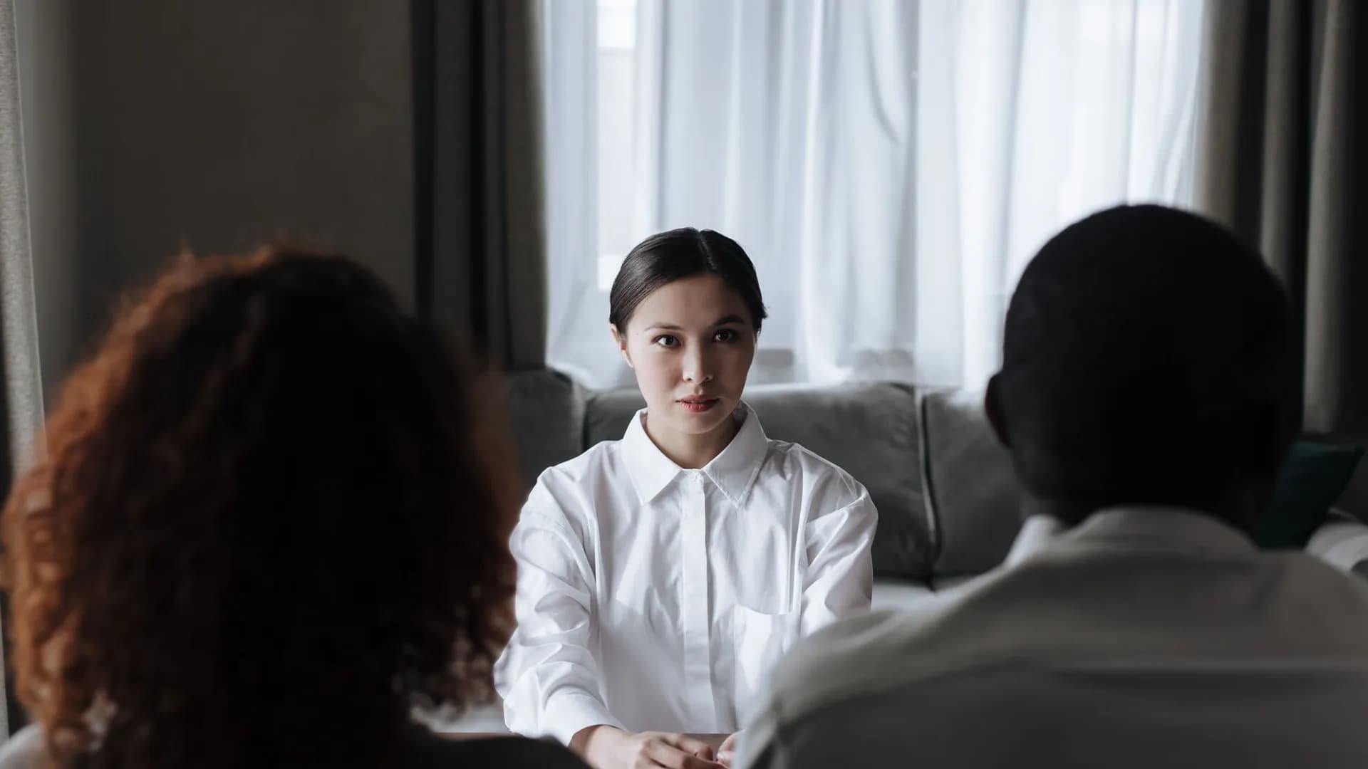 A social worker talks to a diverse couple in a home setting.