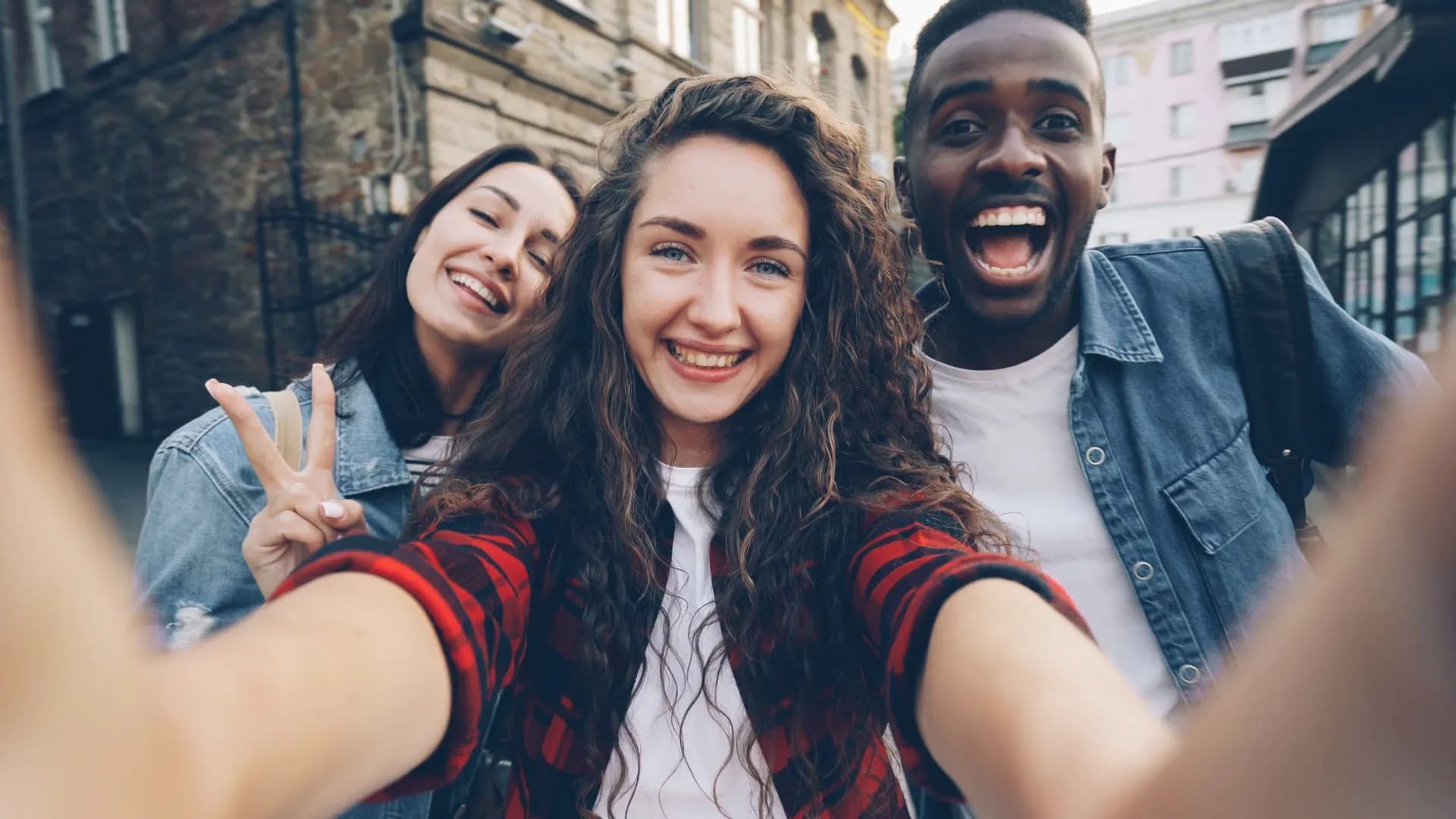 Three friends taking a cheerful selfie in an urban environment. Outdoor fun.