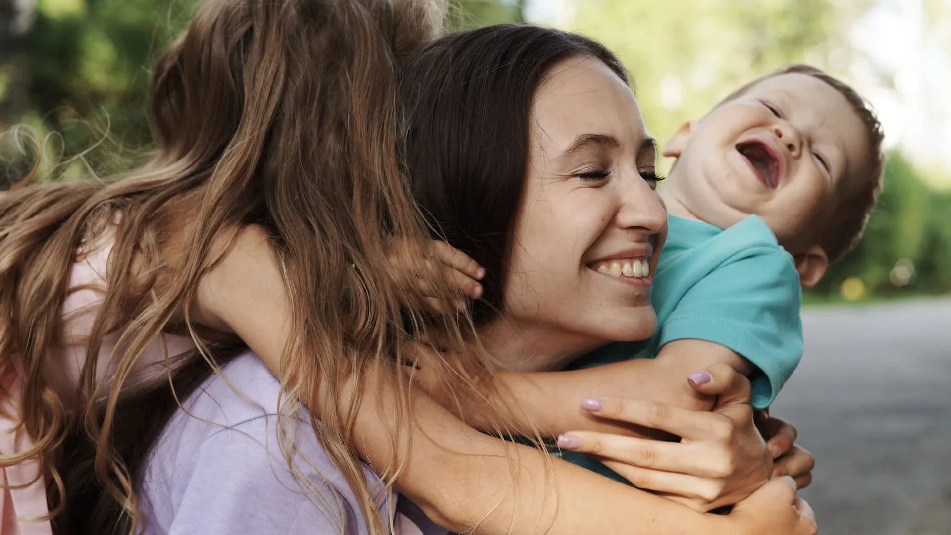 A happy family moment captured with a mother and her children embracing outdoors.