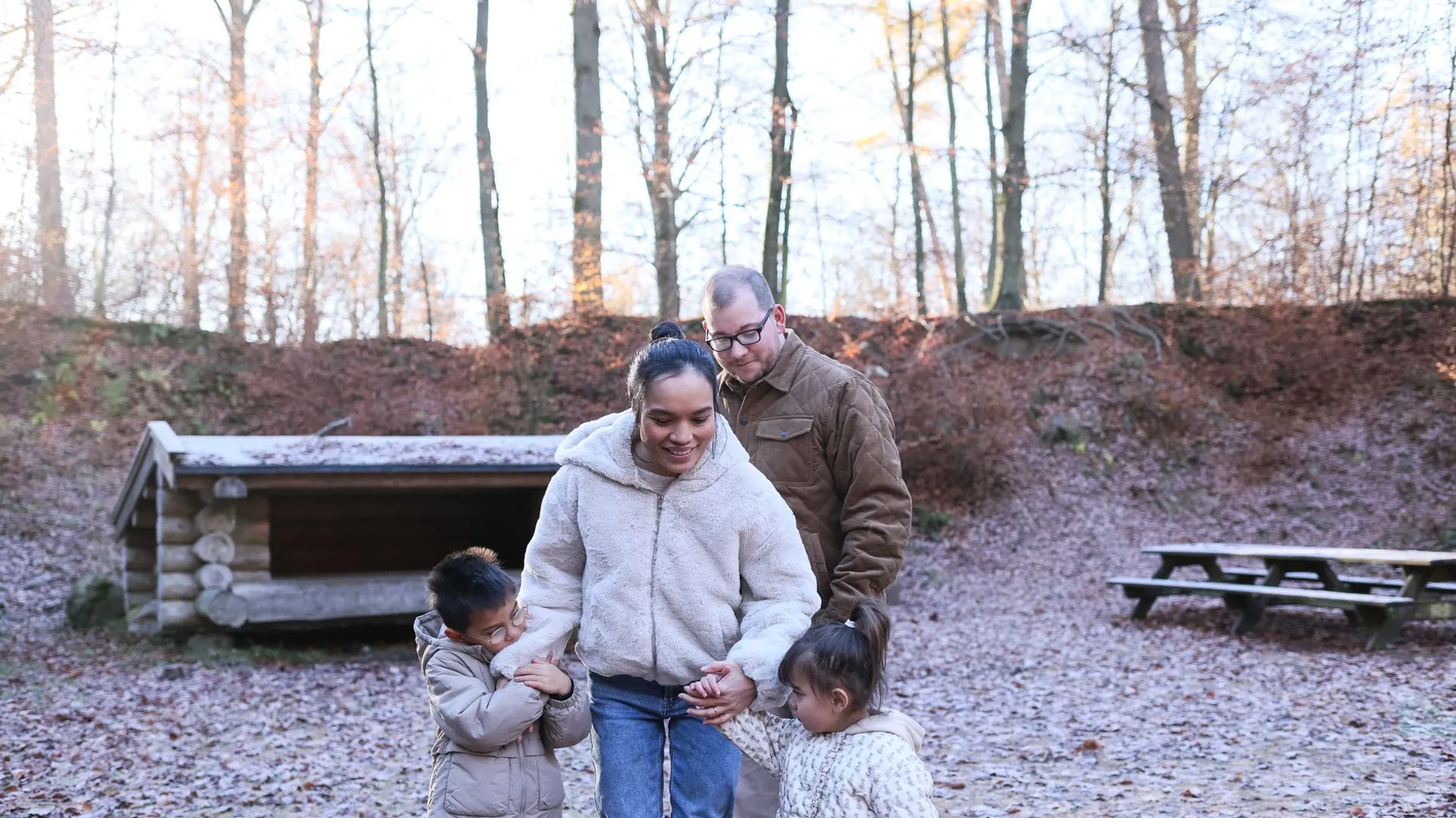 A happy family strolls through an autumn forest, enjoying the outdoors together.