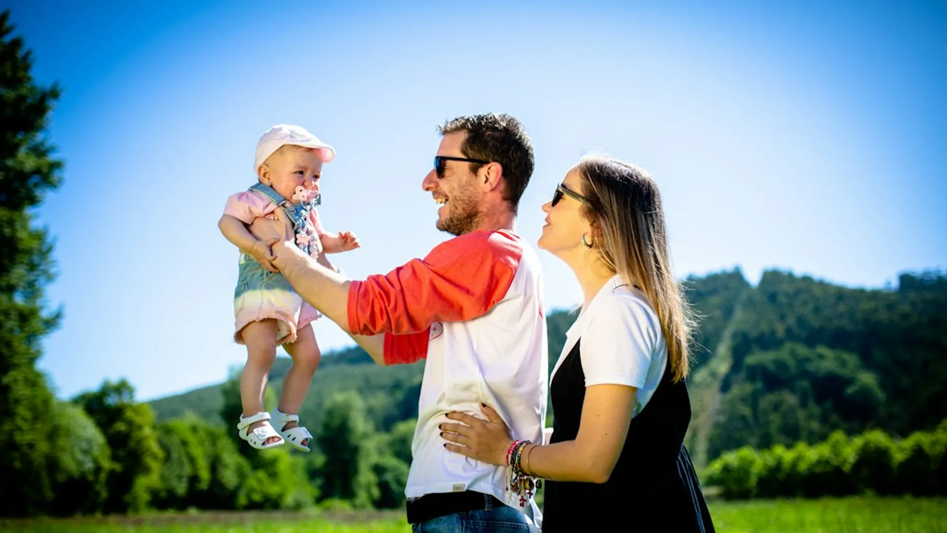 man in white and red polo shirt carrying girl in blue denim jeans during daytime