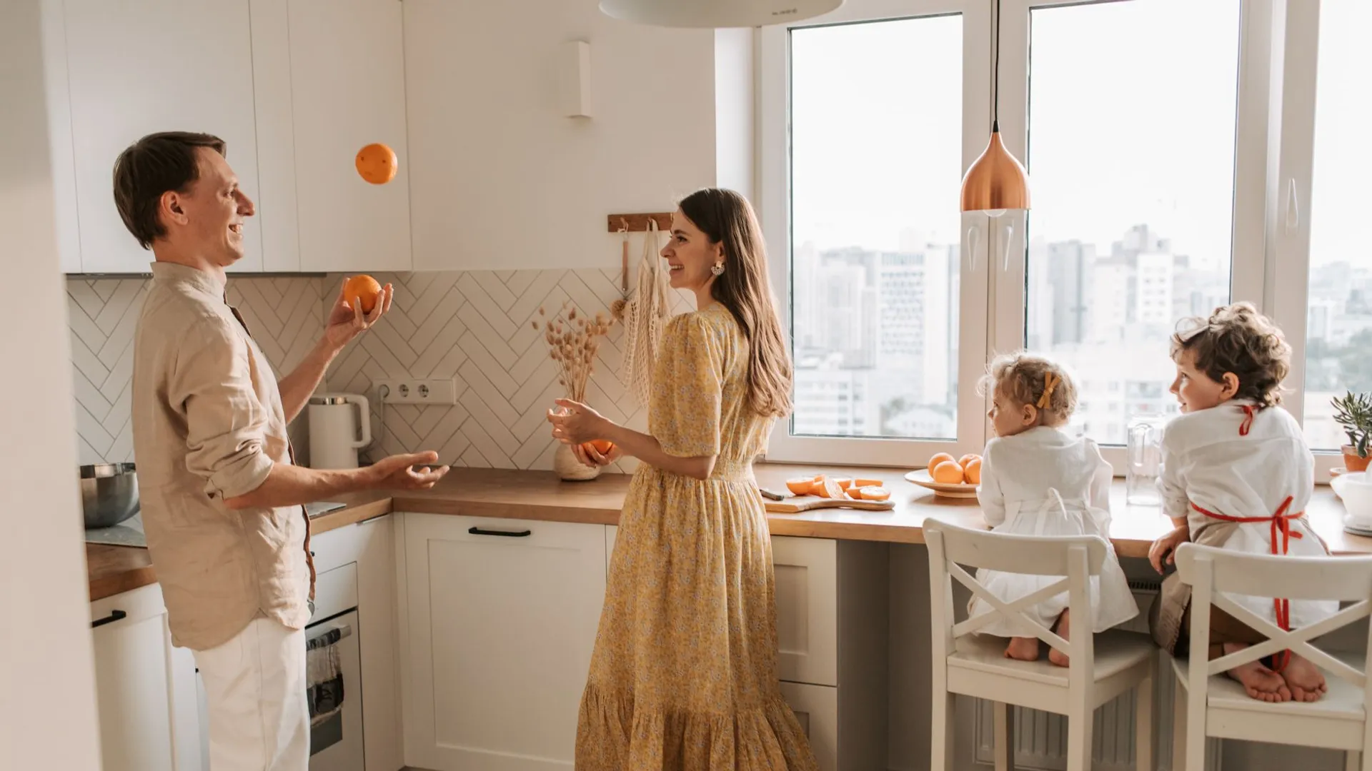 Joyful family scene with parents and children playing in a bright kitchen.