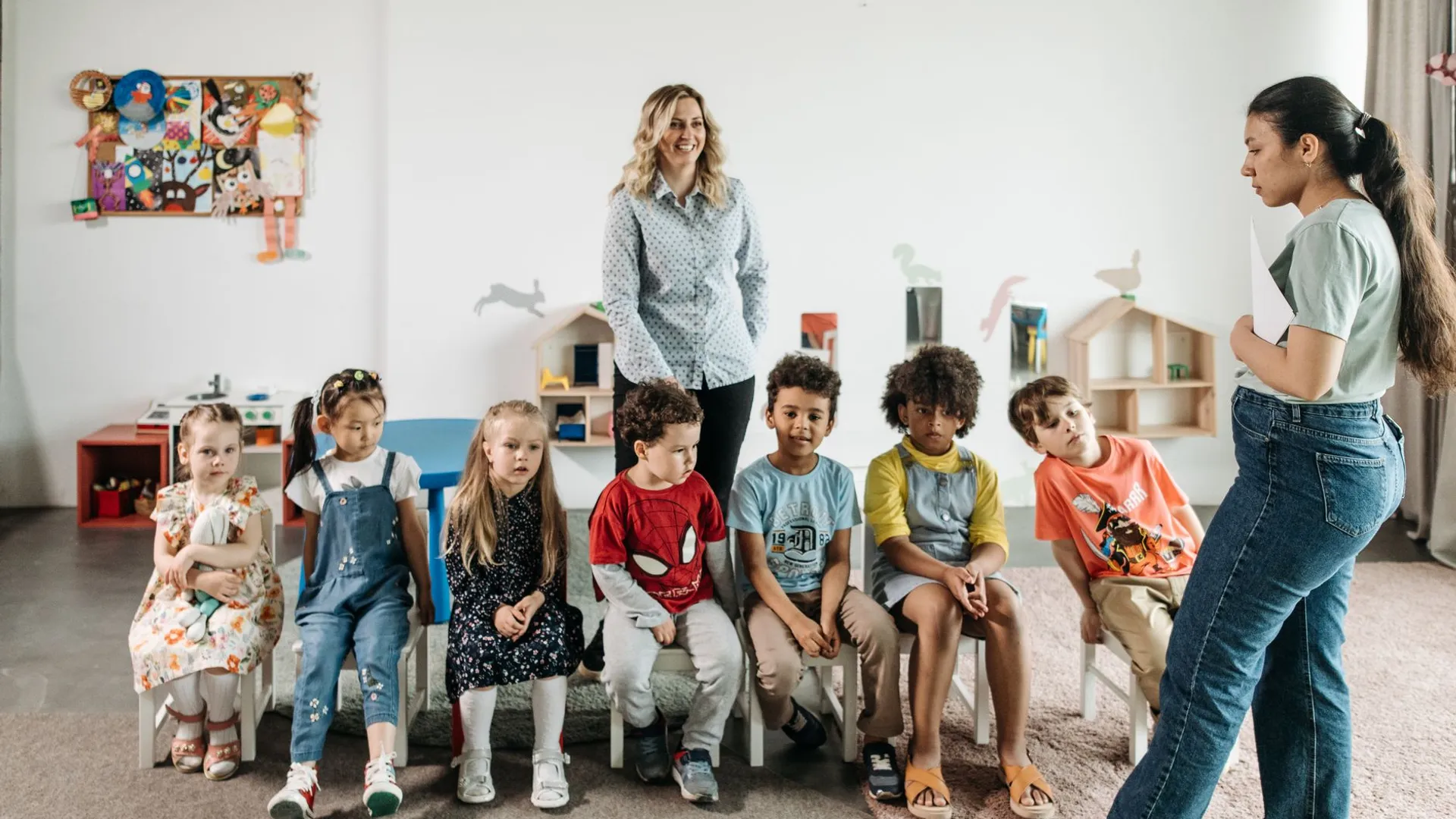 Group of children in a kindergarten classroom attending an interactive learning session with teachers.